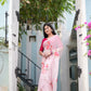 Elegant pink saree for women with floral embroidery, worn by a model at a picturesque entrance