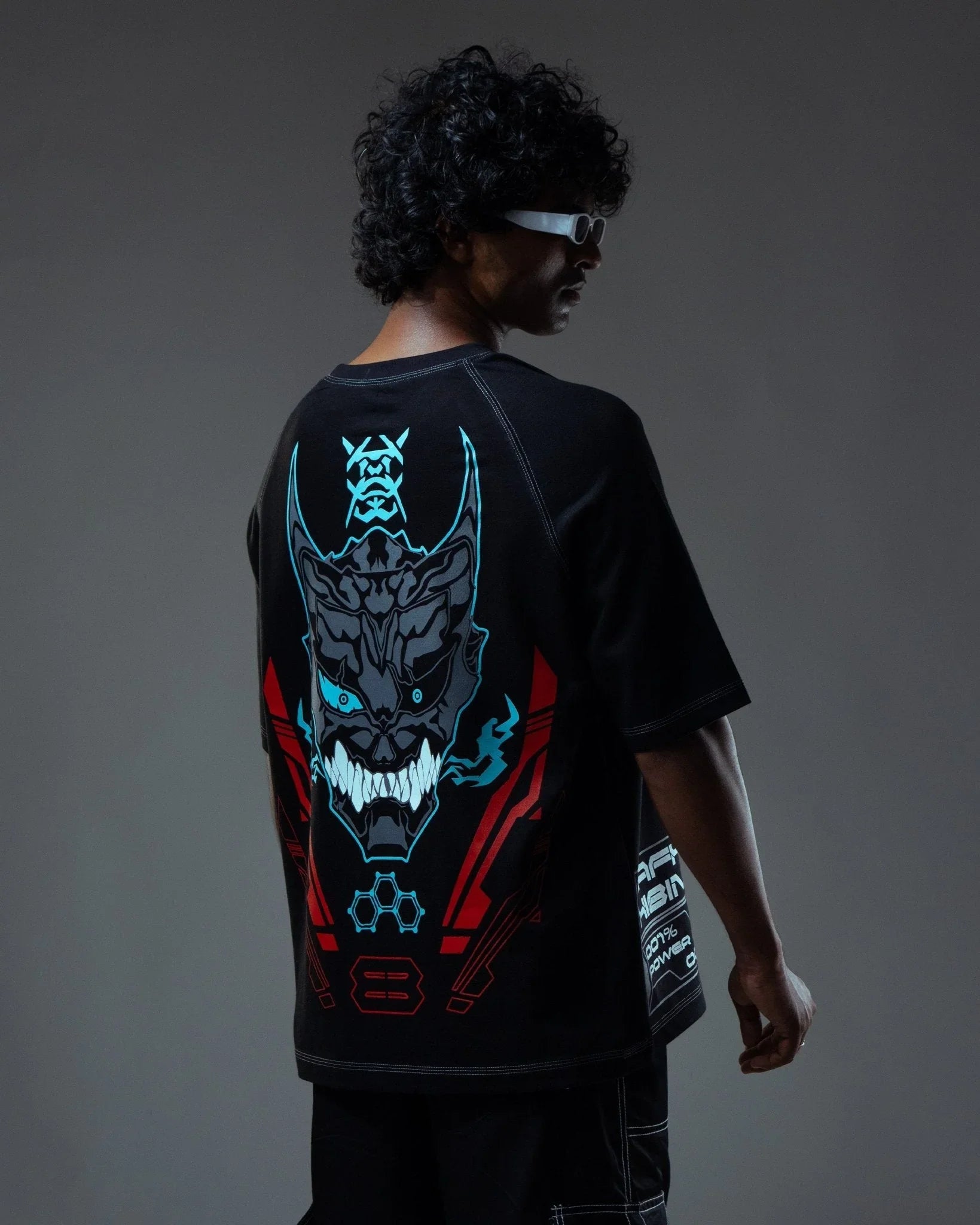 Person wearing a black t-shirt with a glowing dragon design on the back against a dark background