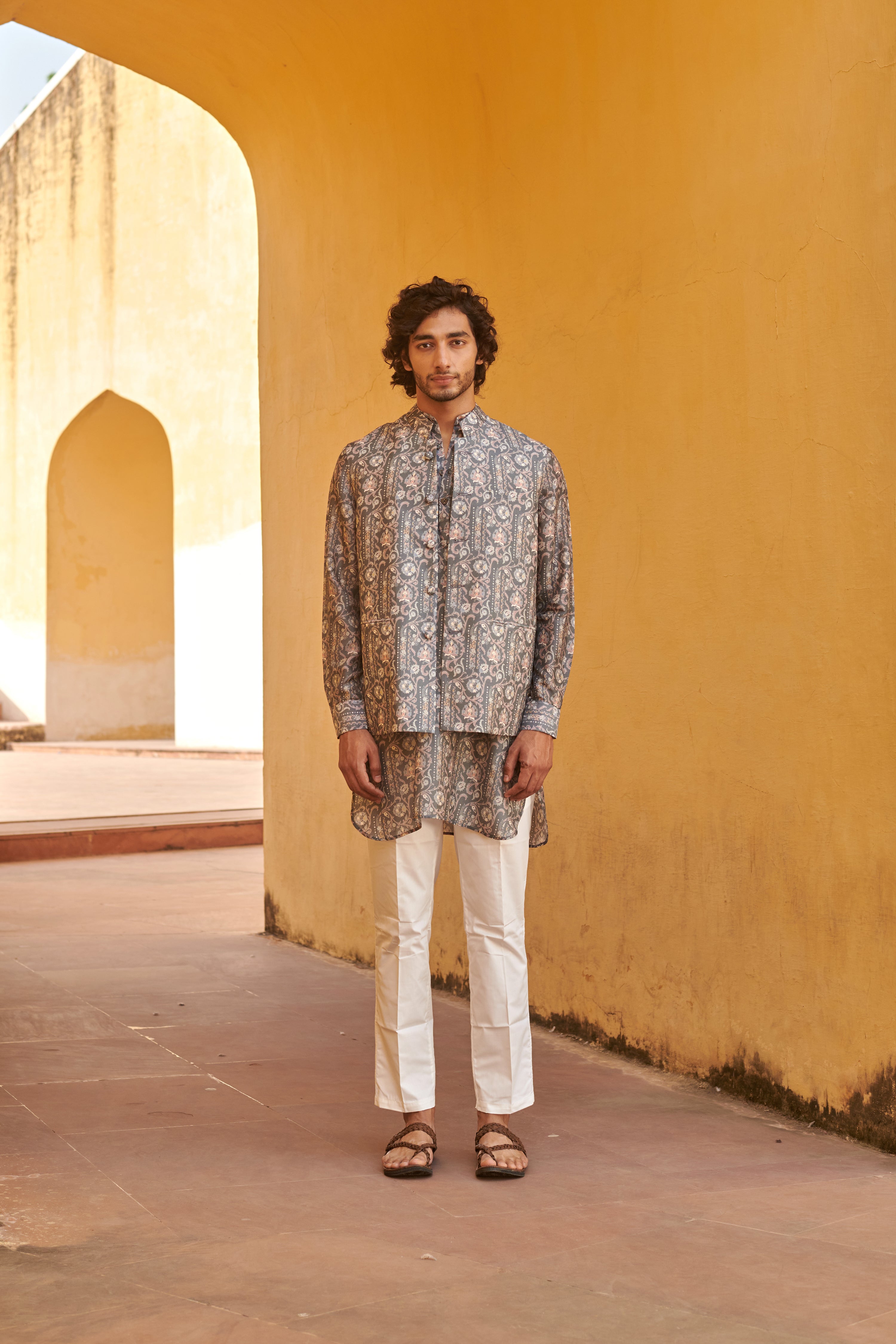 Stylish printed kurta and jacket for men in a traditional setting with a yellow backdrop