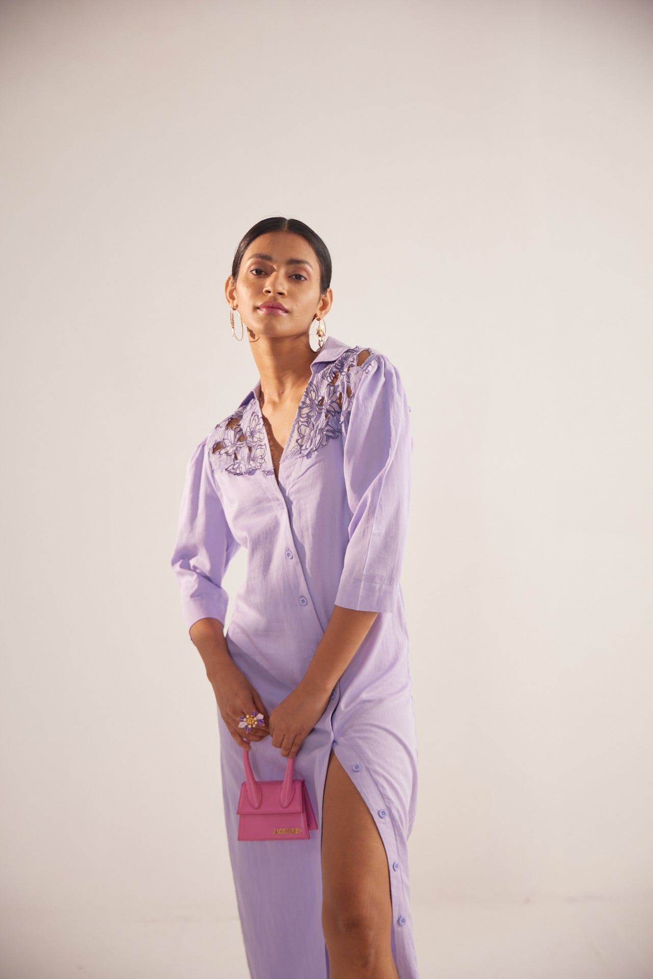 Stylera purple embroidered event dress with three-quarter sleeves and front slit worn with pink handbag