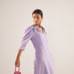 Stylera purple embroidered event dress with three-quarter sleeves worn by model holding a small pink handbag