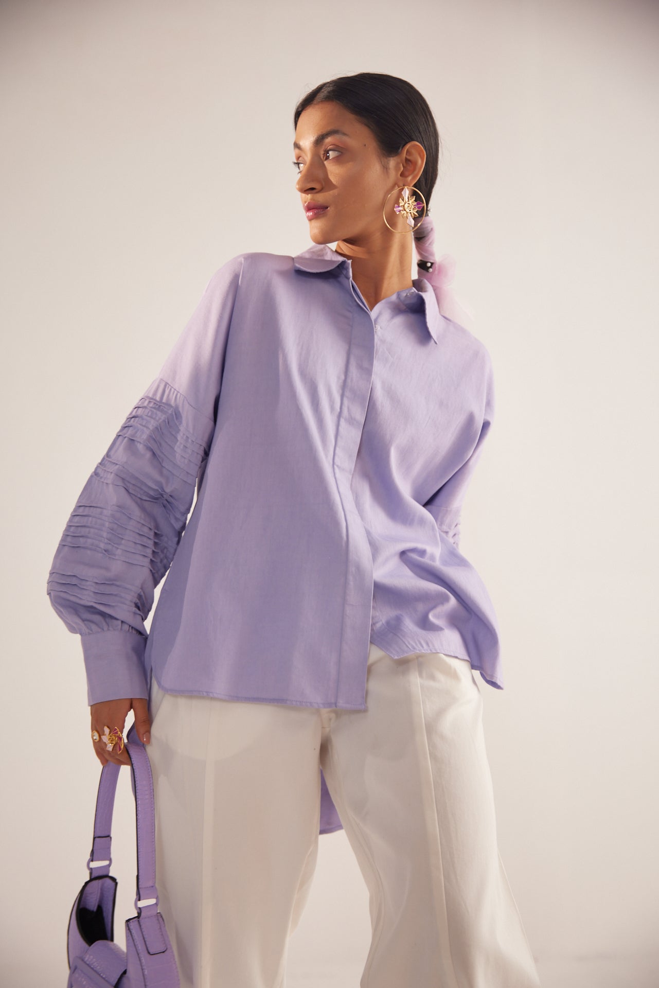 Stylera Era purple oversized cotton shirt with ruched sleeves worn with white pants and purple handbag