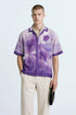 Stylera purple resort shirt for men featuring watercolor floral print short sleeves and camp collar on model