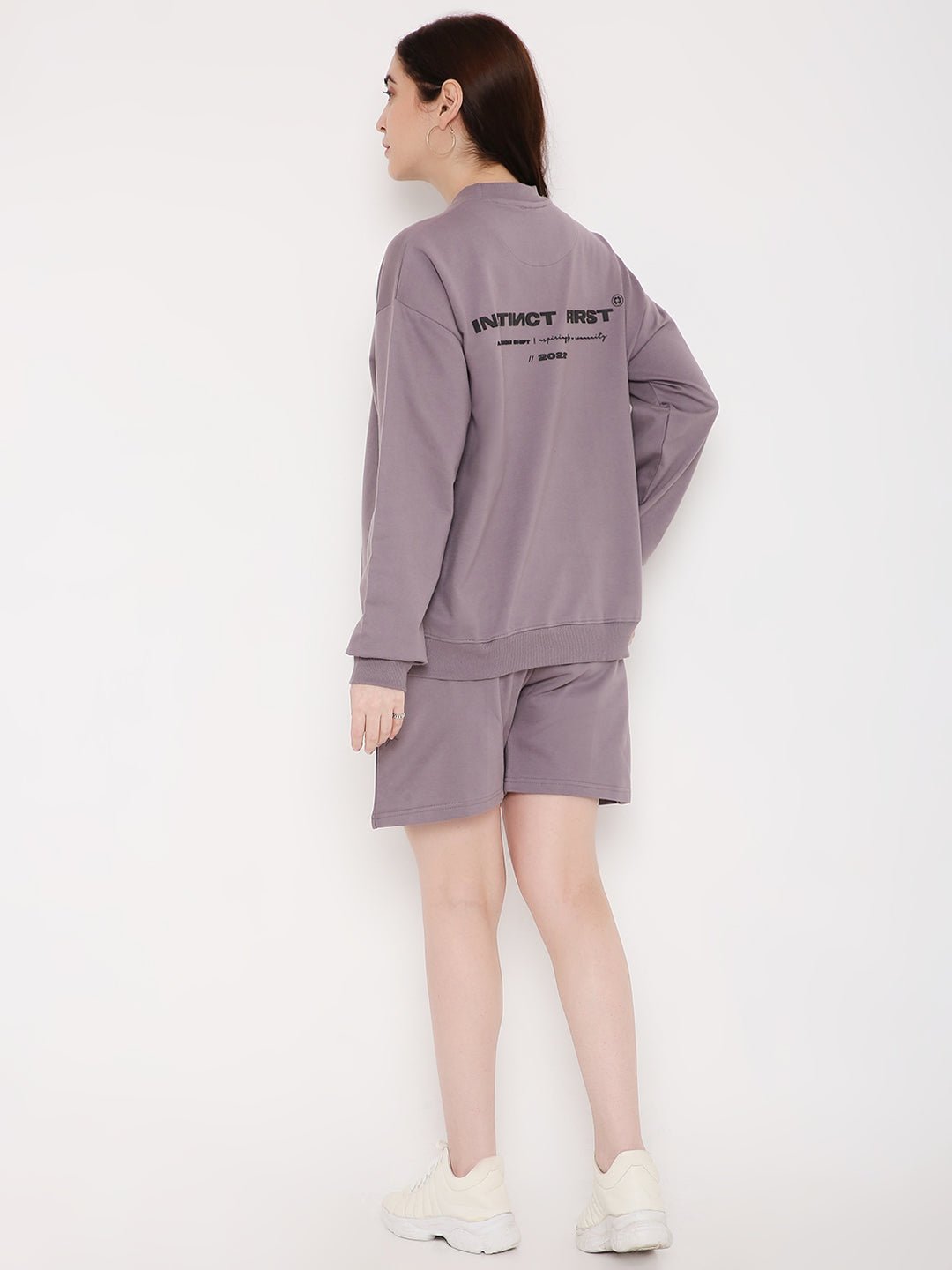 Model wearing Stylera purple sweatshirt for women with matching shorts and white sneakers