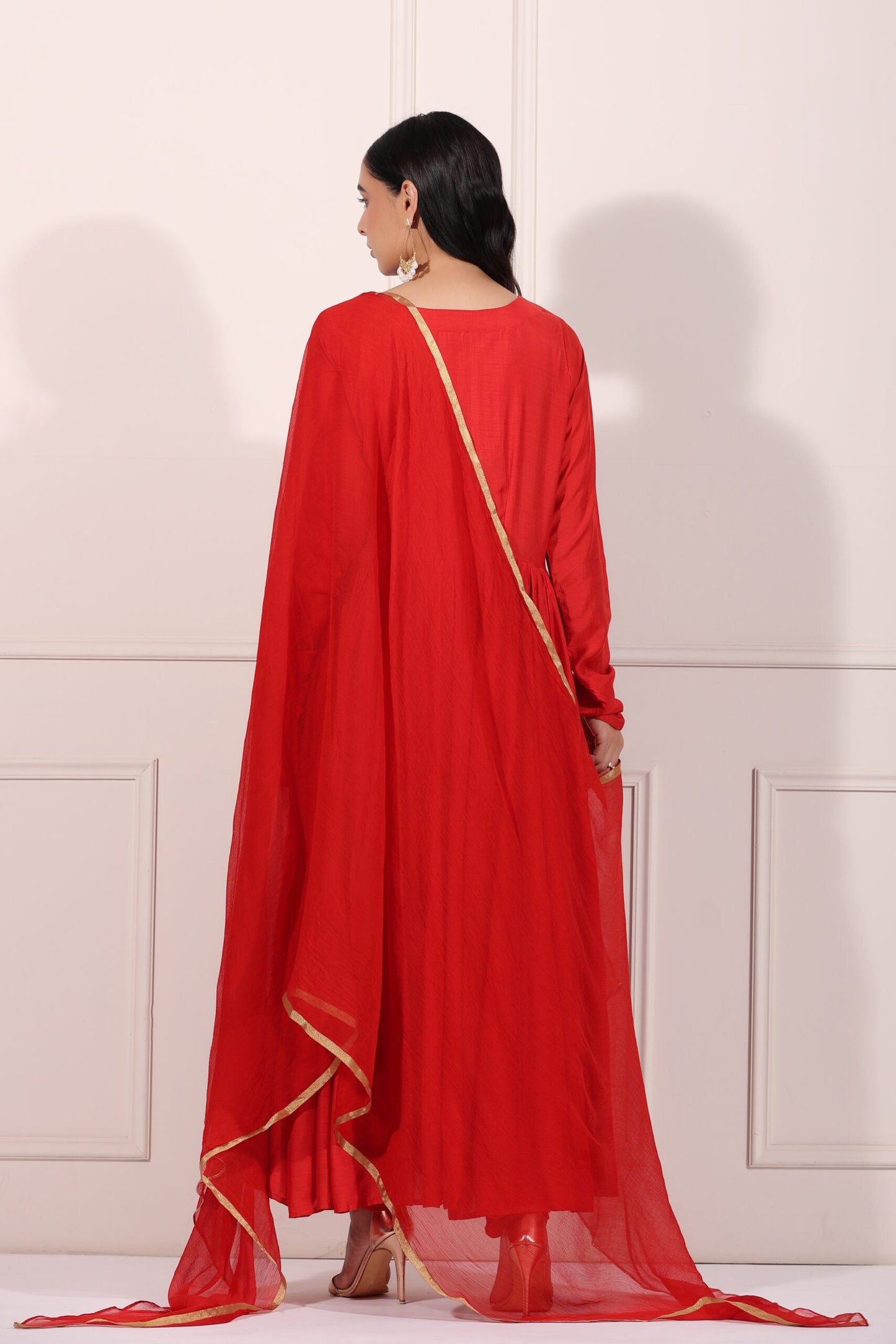 Elegant red festive Anarkali gown with flowing cape and gold detailing, perfect for celebrations