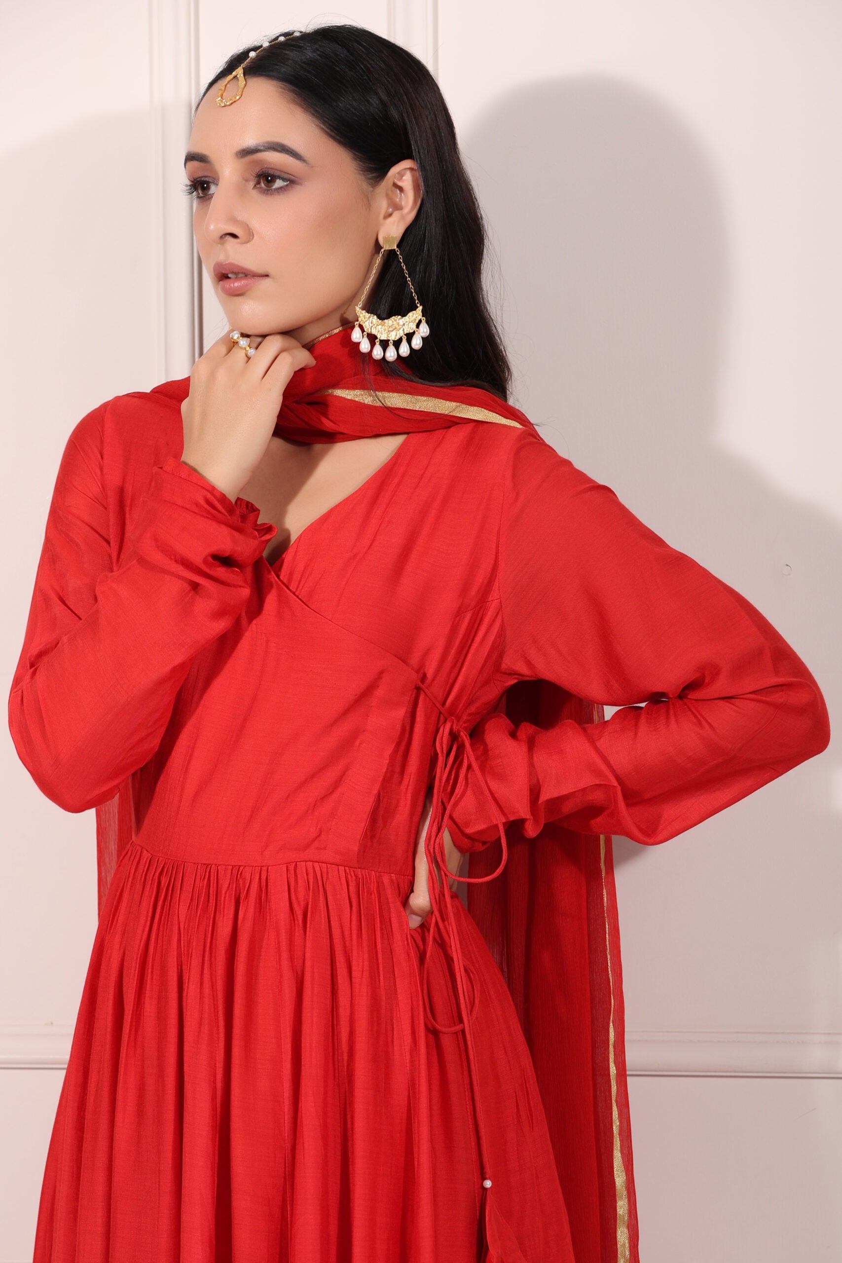 Elegant model wearing a red festive Anarkali gown adorned with traditional accessories