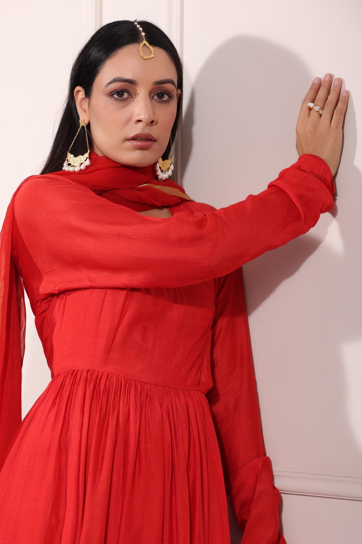 Graceful model wearing a red festive Anarkali gown with elegant accessories and a modest pose