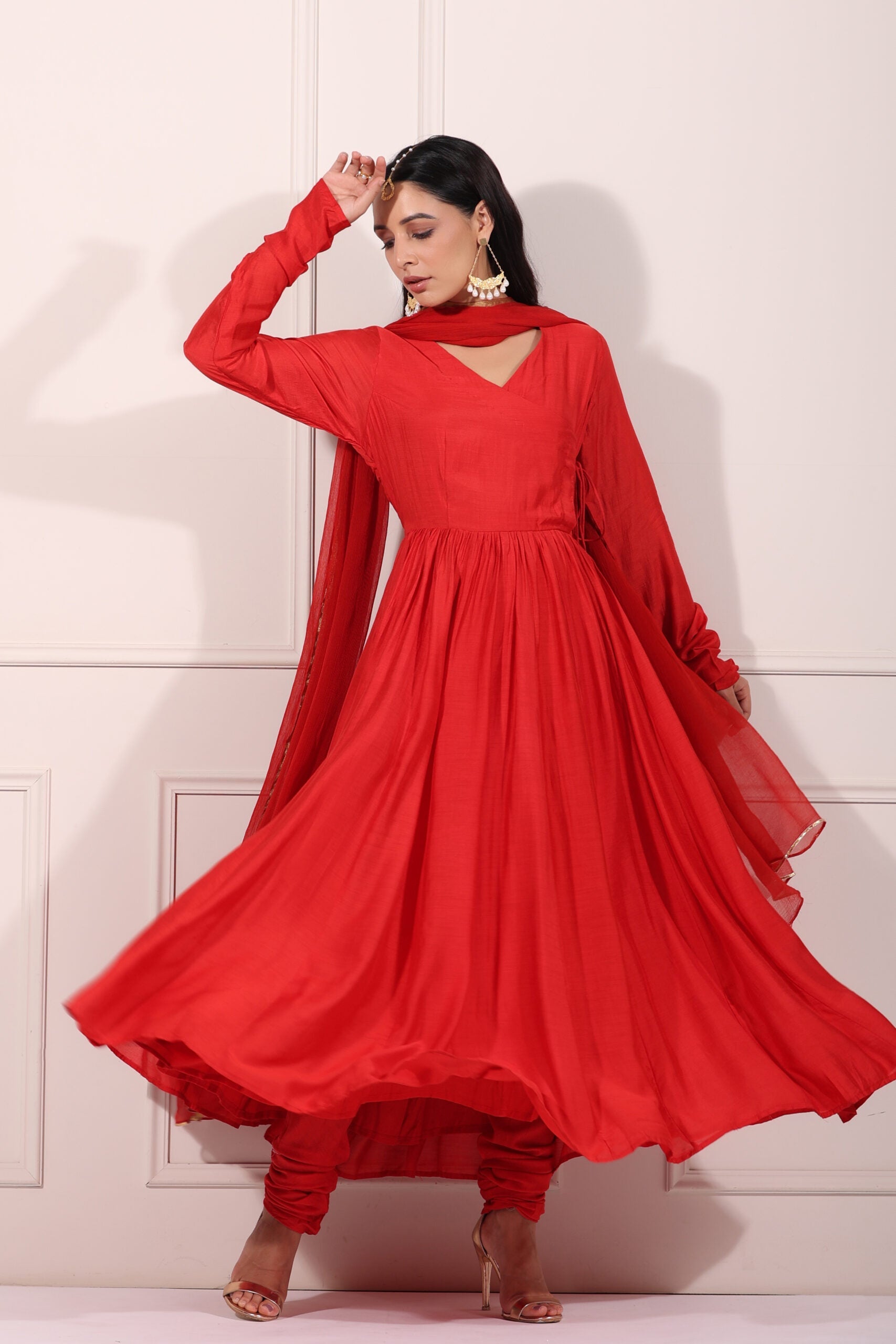 Model wearing a flowing red festive Anarkali gown, showcasing elegant design and graceful movement