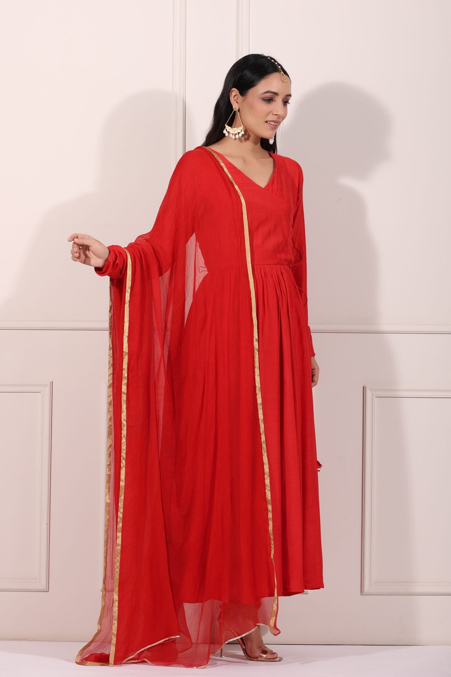 Elegant woman in a red festive Anarkali gown with a flowing silhouette and gold accents