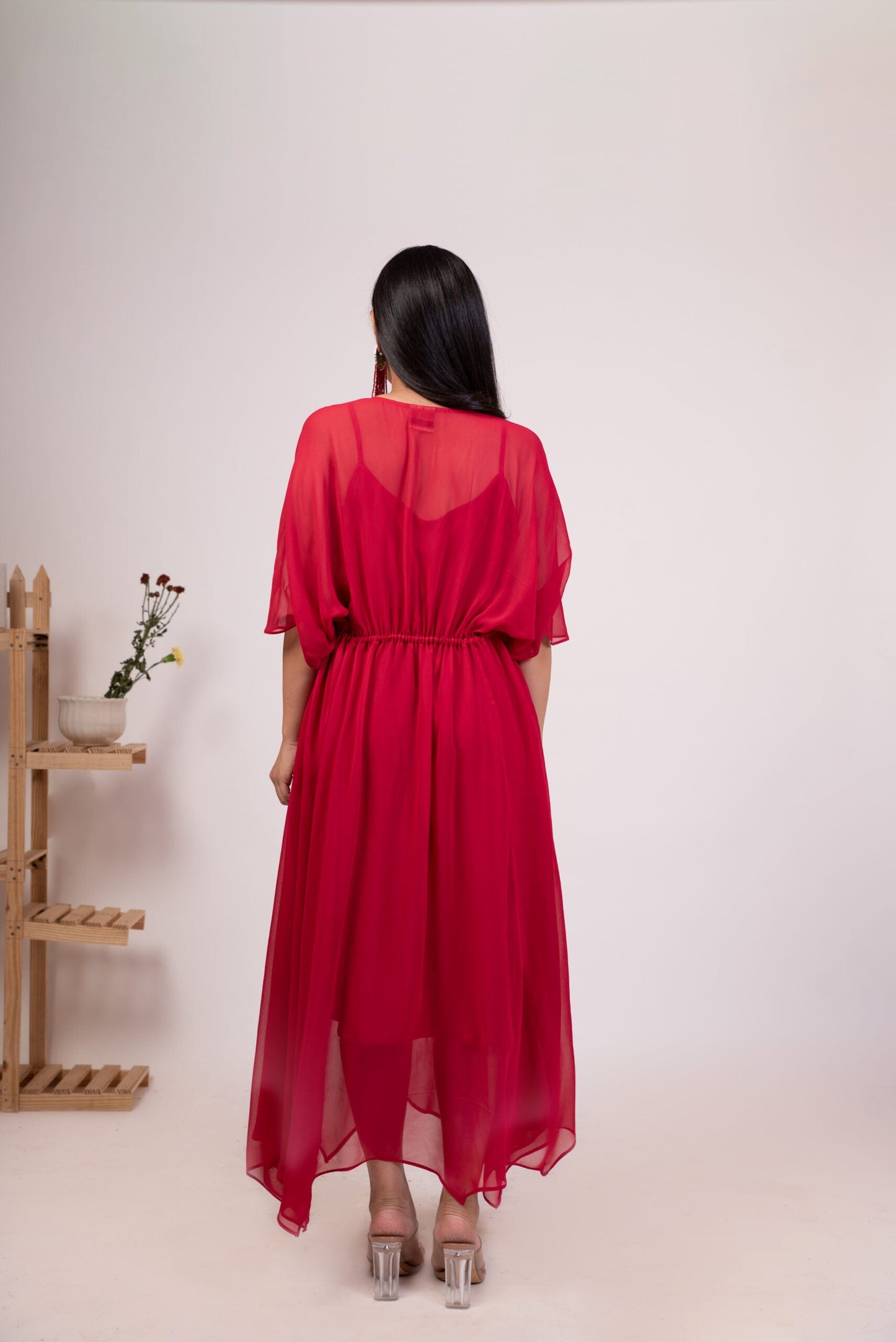 Elegant back view of a red flowy dress for women with a cinched waist and sheer fabric