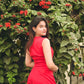 Model wearing red two piece set for women sleeveless crop top and high waisted shorts outdoors by flowering hedge