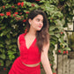 Model wearing a red two piece set for women with sleeveless V neck crop top and matching mini skirt in garden