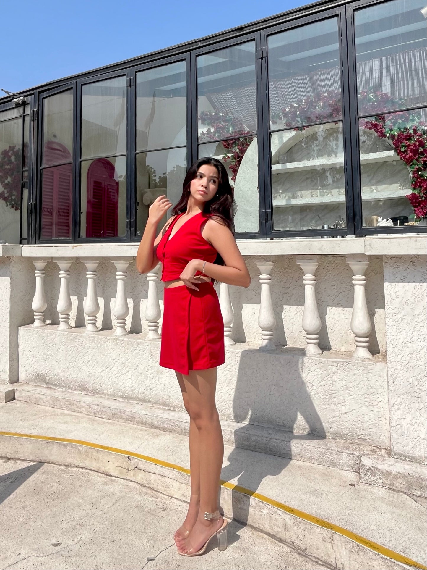 Woman on sunlit terrace wearing red two piece set for women crop sleeveless top and wrap skirt with clear heels