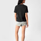 Woman wearing a regular fit black t-shirt for women by Stylera paired with denim shorts and sneakers