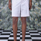Stylera regular fit pearl grey shorts worn by model with black sandals on checkered floor