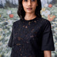 Model wearing Stylera relaxed fit black dress for women with short sleeves and floral cutout overlay