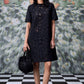 Stylera model wearing relaxed fit black dress for women with floral eyelet cutouts and black handbag