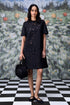 Stylera model wearing relaxed fit black dress for women with floral eyelet cutouts and black handbag