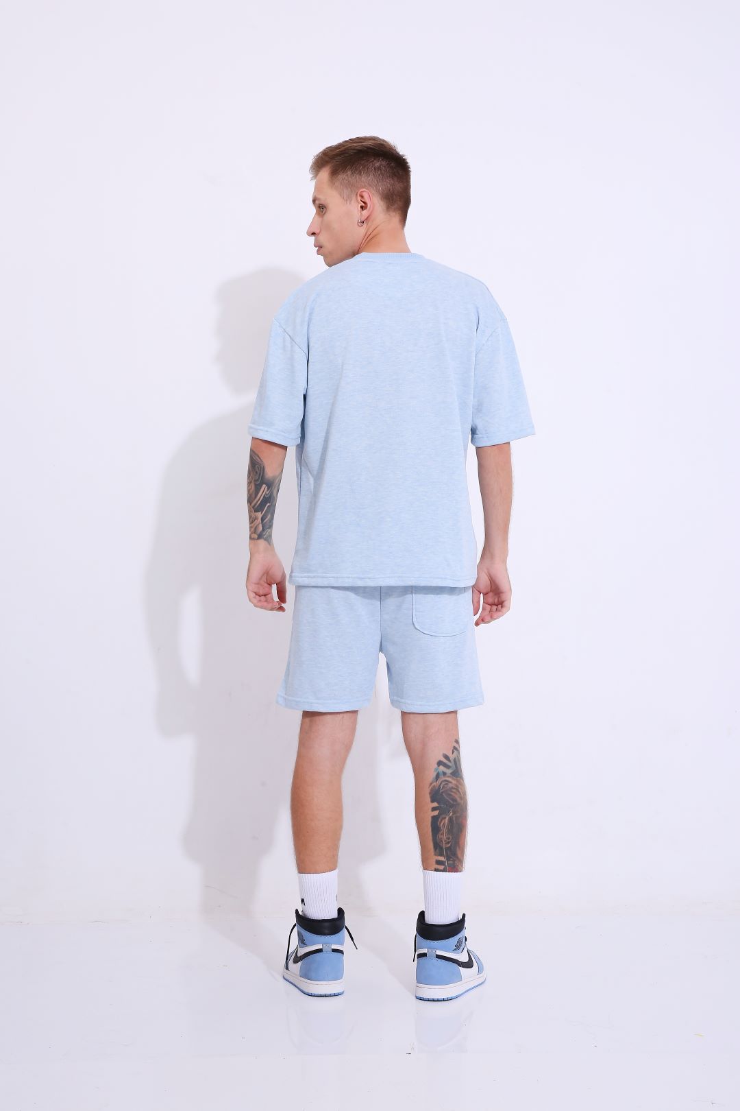 Stylera model wearing retro blue oversized t-shirt with matching shorts seen from back