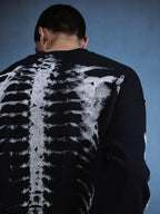 Person wearing a sweater with a skeleton design on the back against a blue background