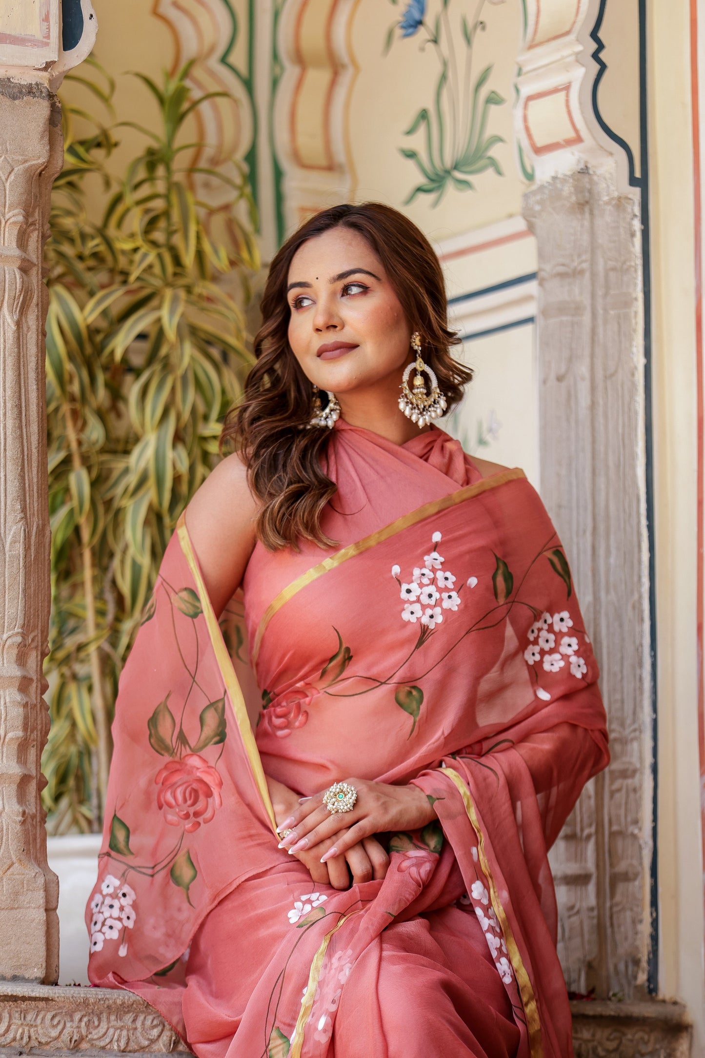Elegant rust saree with floral hand painting draped beautifully on a model, showcasing intricate designs.