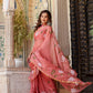 Elegant rust saree with floral hand painting showcased by a model in a beautiful setting