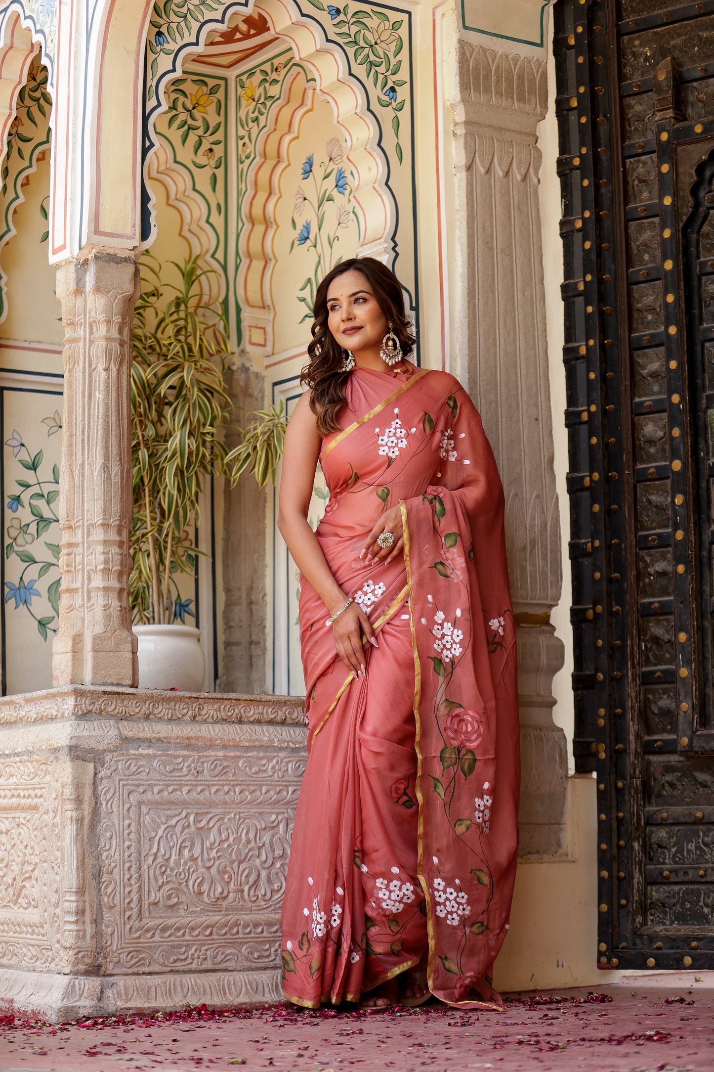 Elegant rust saree with floral hand painting, beautifully styled for traditional occasions