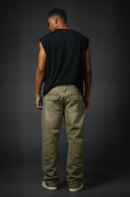 Man wearing a black sleeveless shirt and beige pants against a dark background