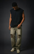 Man wearing a black sleeveless shirt and light-colored jeans against a dark background