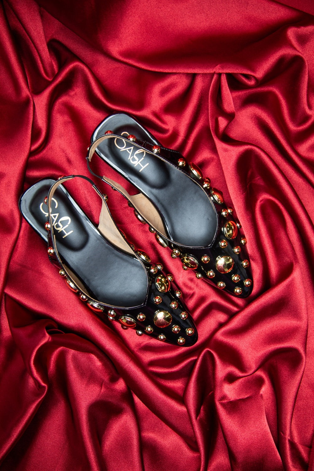 stylera black heels with gold studs on red satin background trendy gold accent footwear