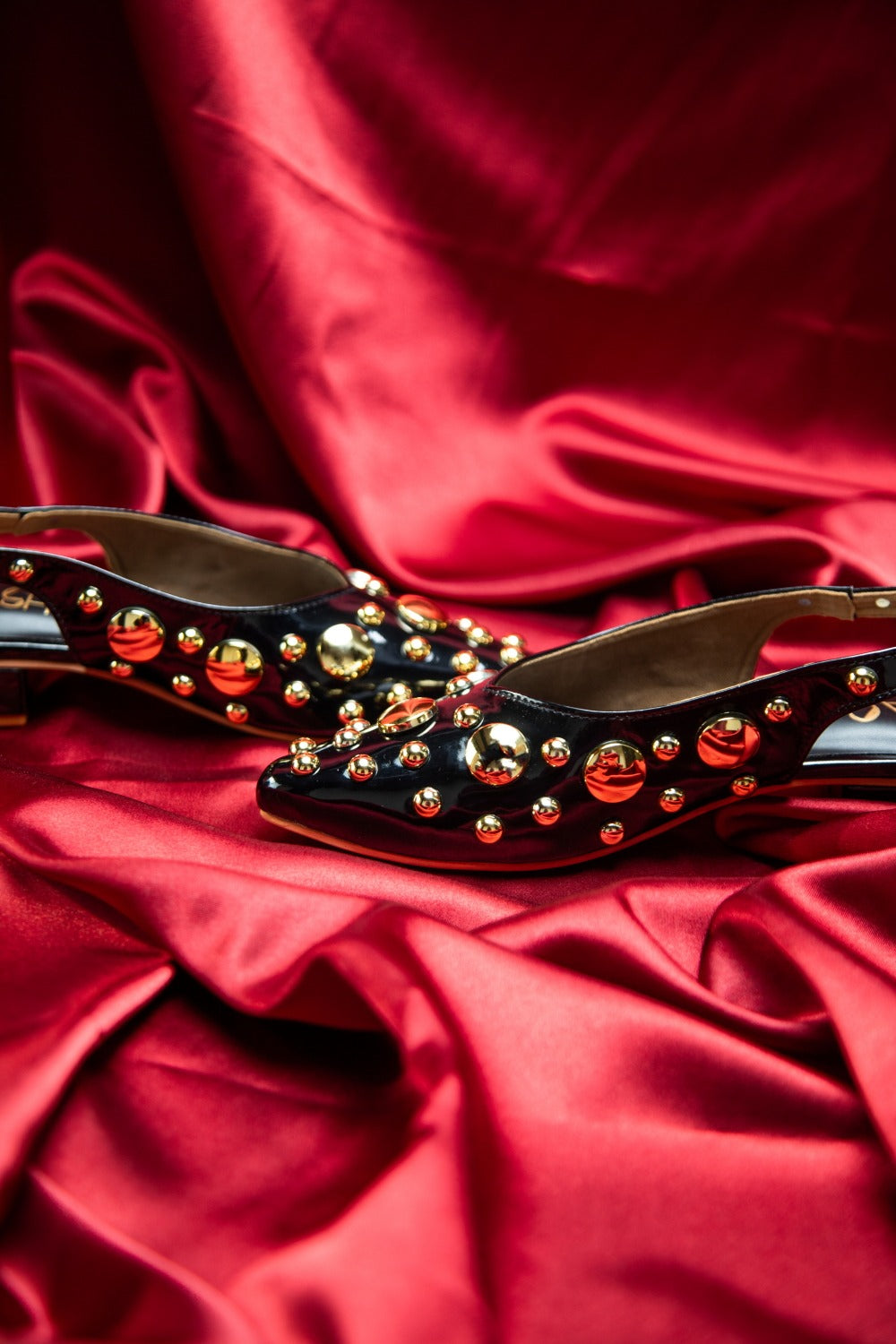 Stylera black heels with gold studs on red satin background trendy gold accent footwear