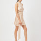 Woman wearing a champagne satin halter mini dress by Stylera with a waist tie and black heeled sandals