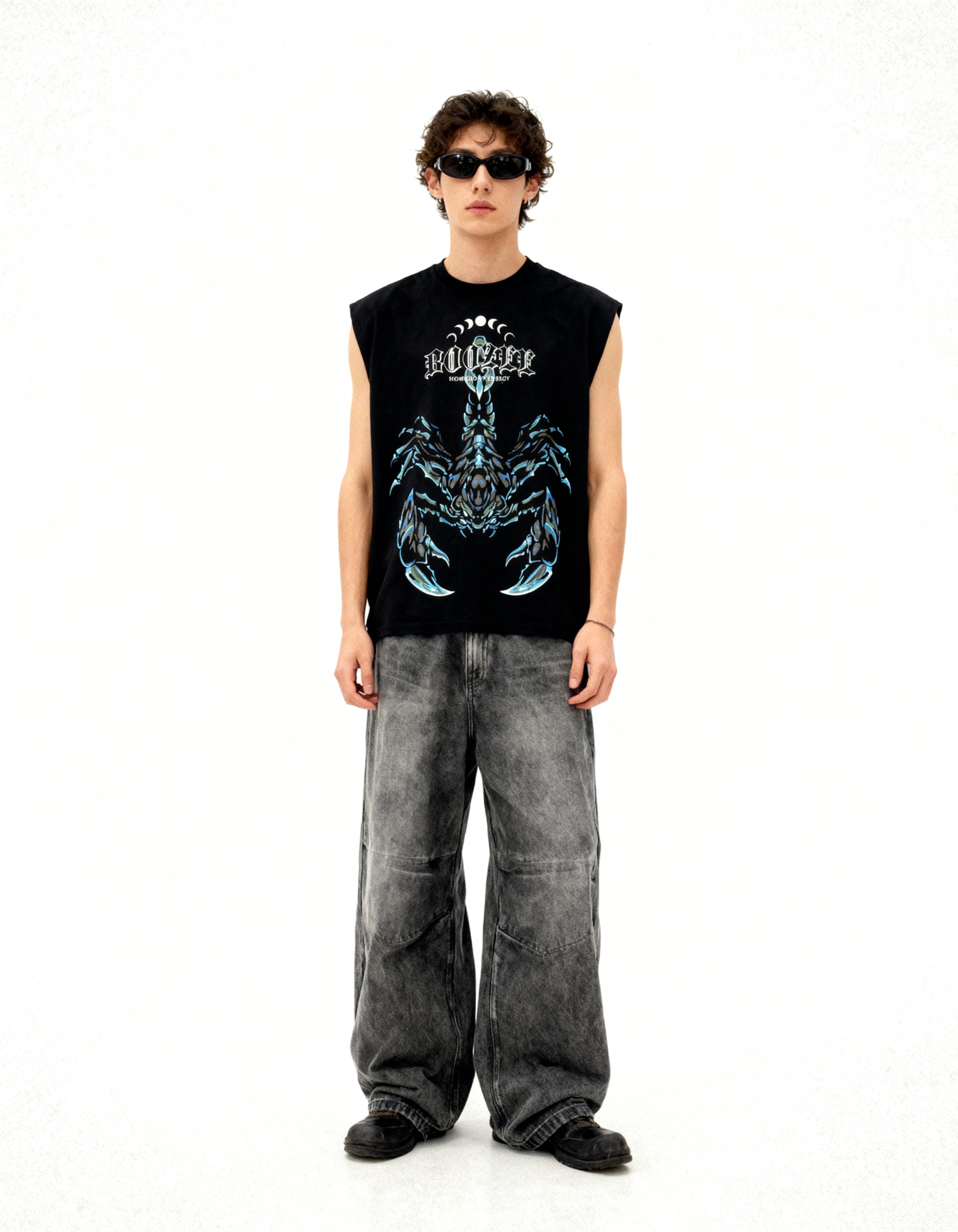 Person wearing a black sleeveless shirt with a graphic design and gray pants on a white background
