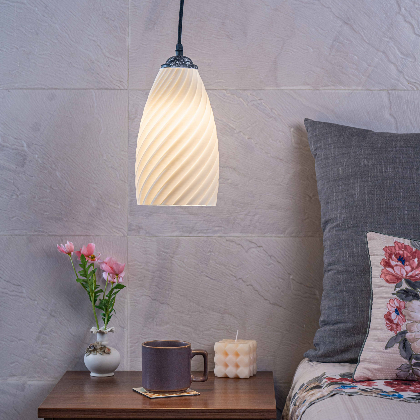 Sculpted white hanging lamp illuminating a cozy bedroom with a bedside table and decorative items
