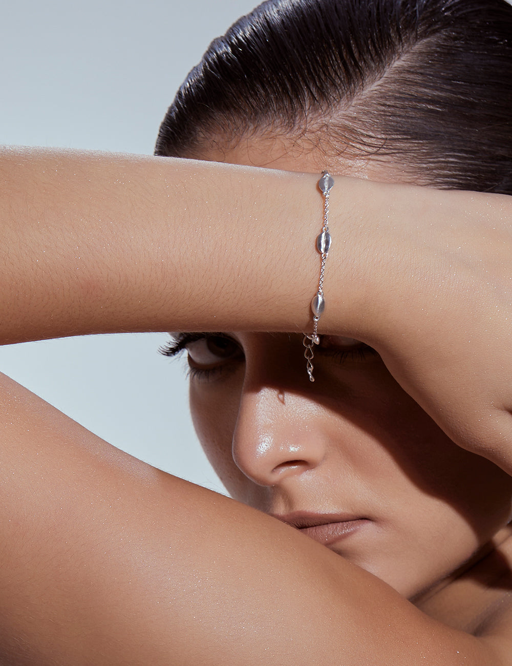Stylera silver bean bracelet on model wrist with delicate chain and small bean beads