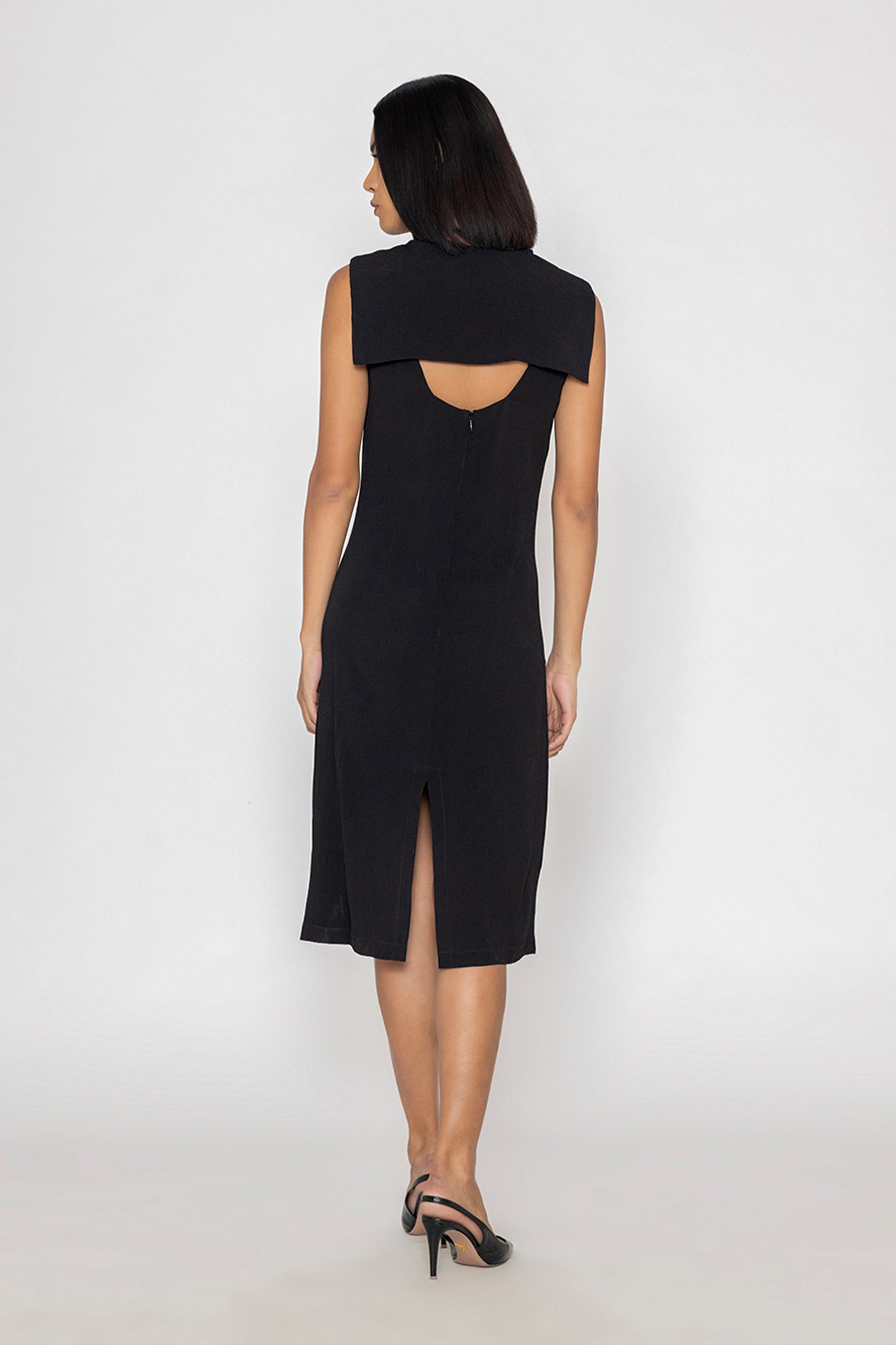 Back view of a model wearing Stylera sleek black evening dress with sleeveless design and back slit