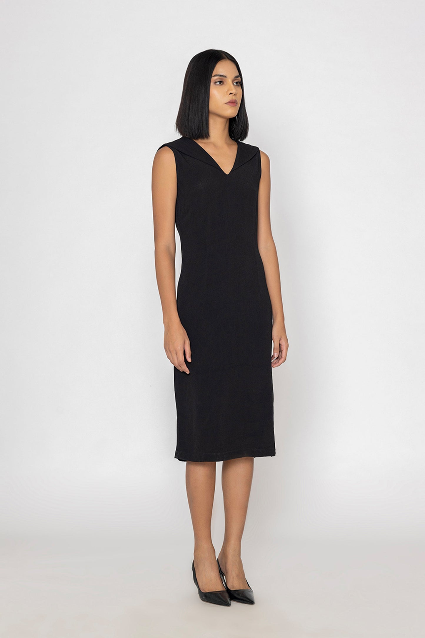 Stylera sleek black evening dress sleeveless V-neck midi length worn with black heels