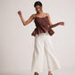 Stylera sleeveless peplum blouse for women in brown paired with white wide-leg pants