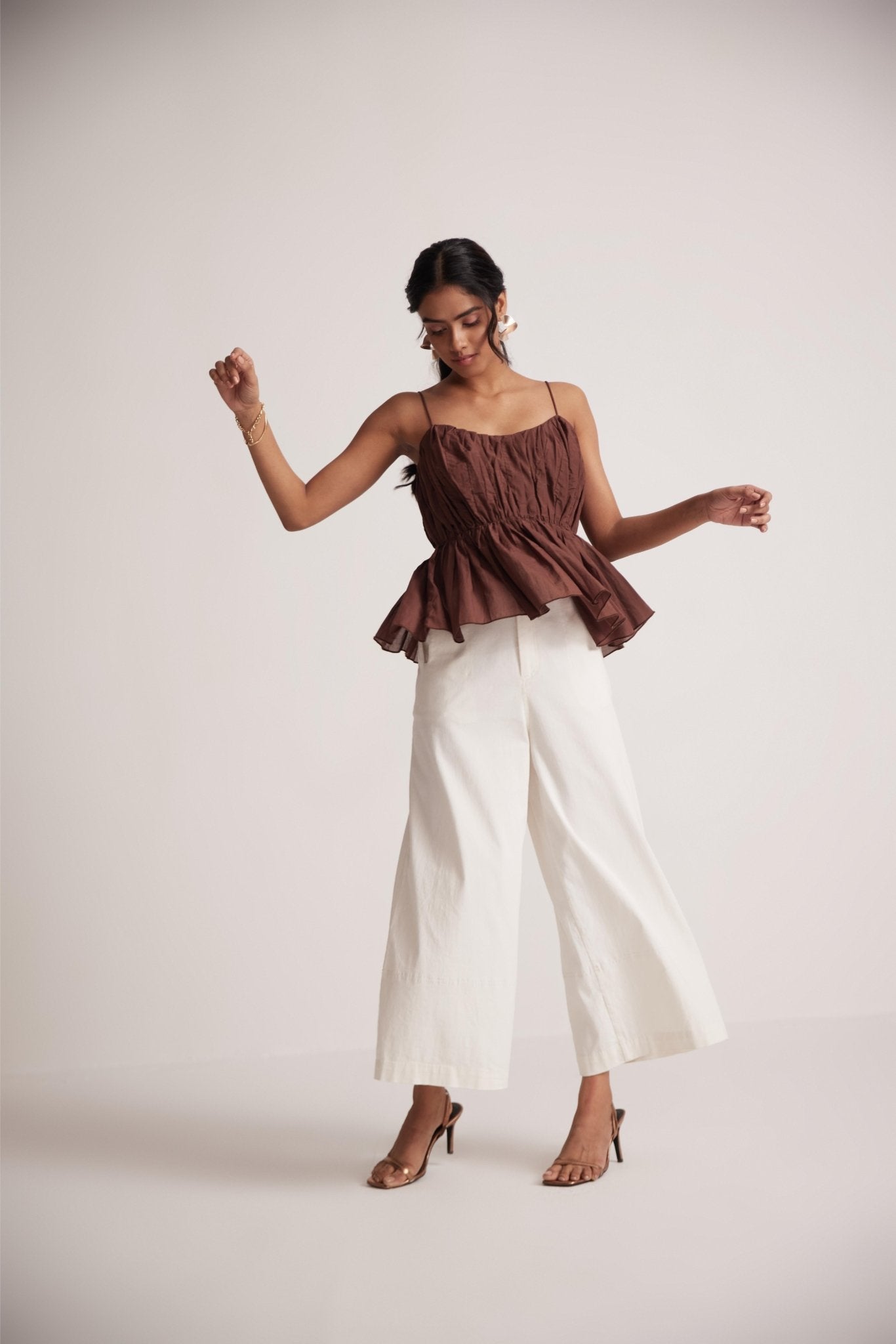 Stylera sleeveless peplum blouse for women in brown paired with white wide-leg pants