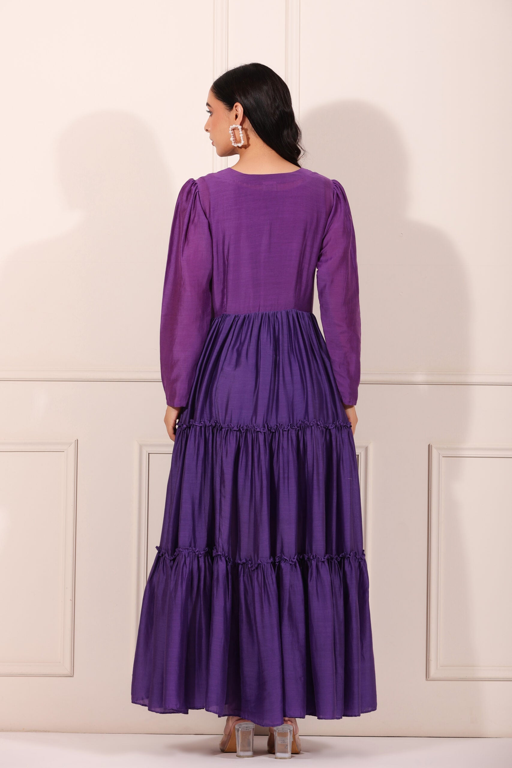 Back view of a solid purple flowy dress for women with long sleeves and tiered design