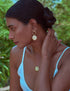 Stylera model wearing gold statement moon earrings with matching pendant necklace and ring outdoors