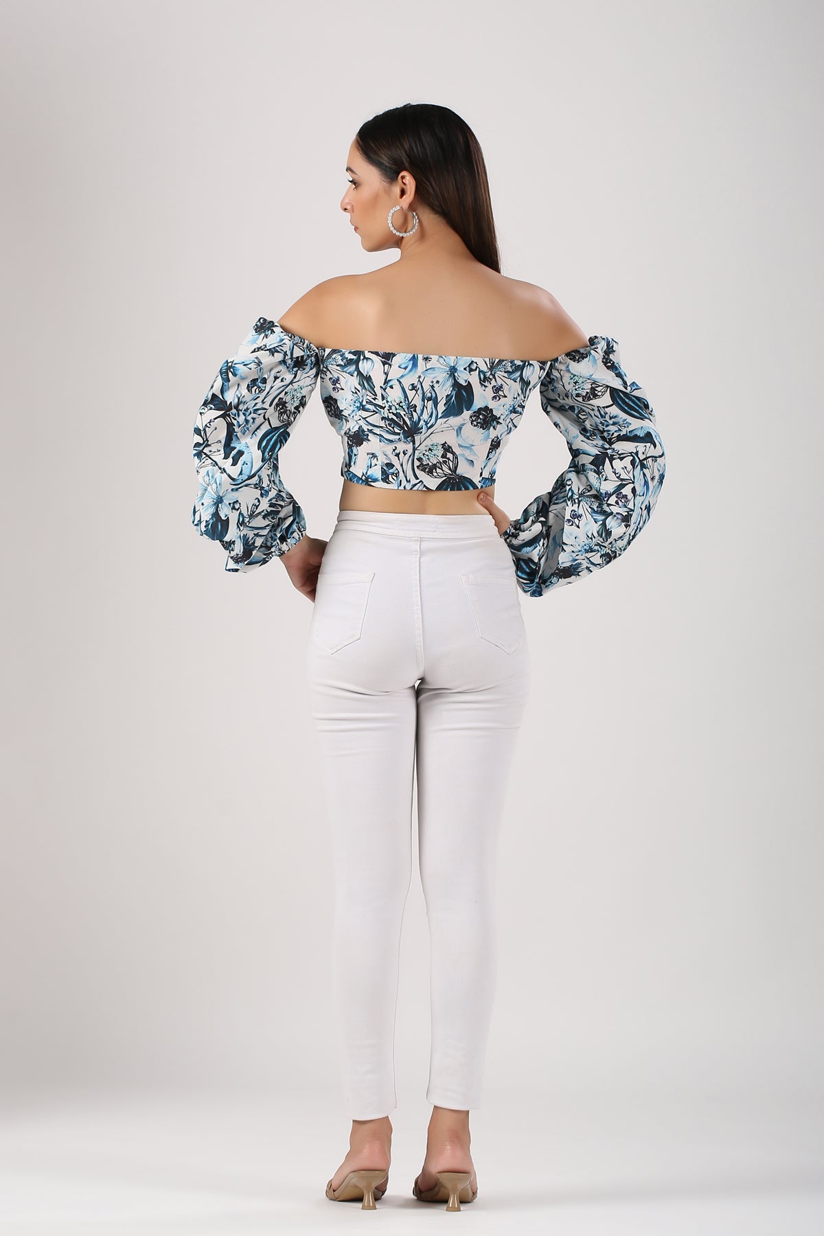 Back view of Stylera statement sleeve crop top with floral print and puff sleeves paired with white pants