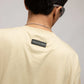 Back view of model wearing Stylera cream crewneck with branded neck label stencil art t-shirt relaxed fit