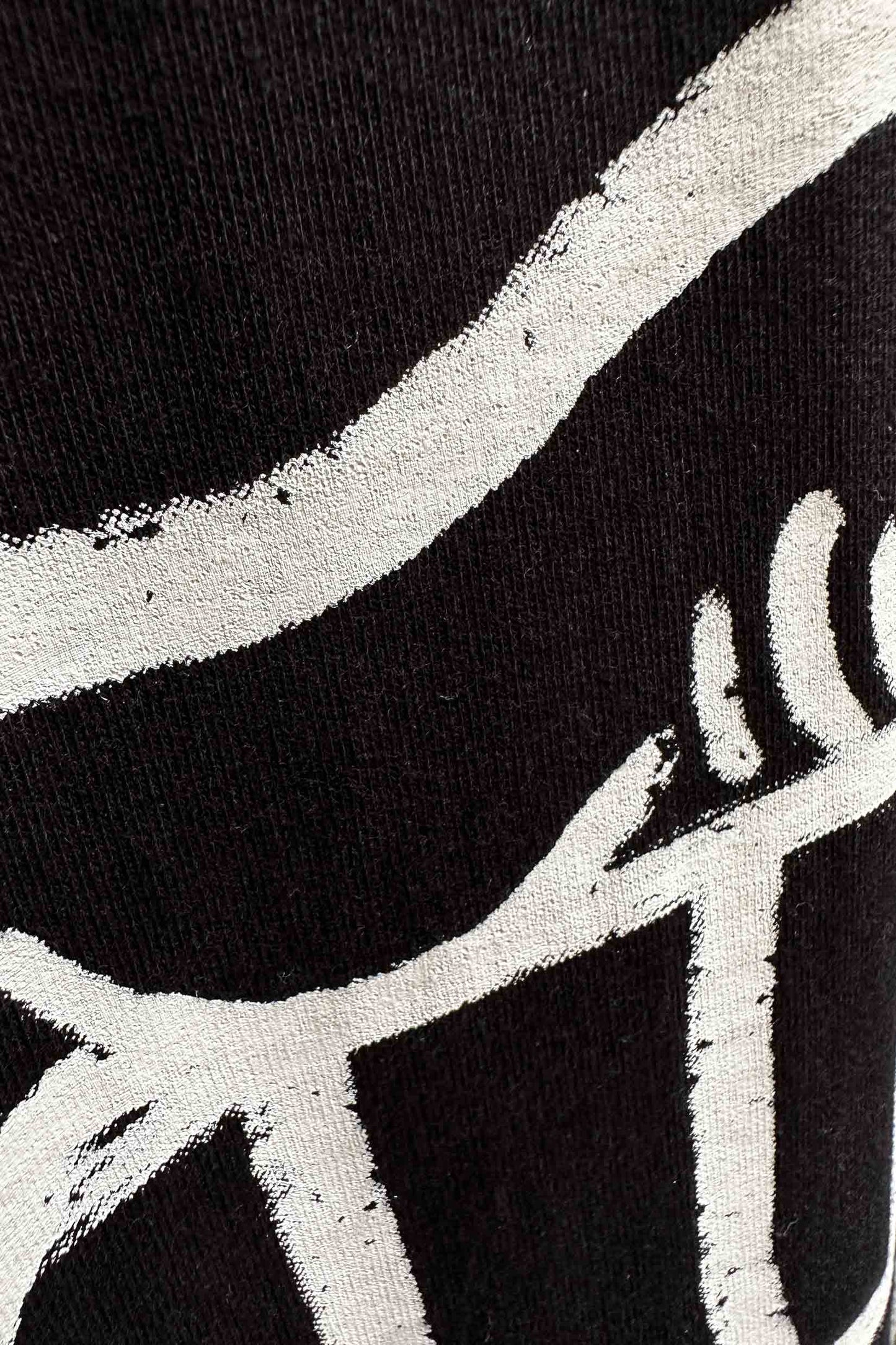 Stylera black T shirt close up showing white brushstroke abstract print on fabric trendy oversized art tee for men