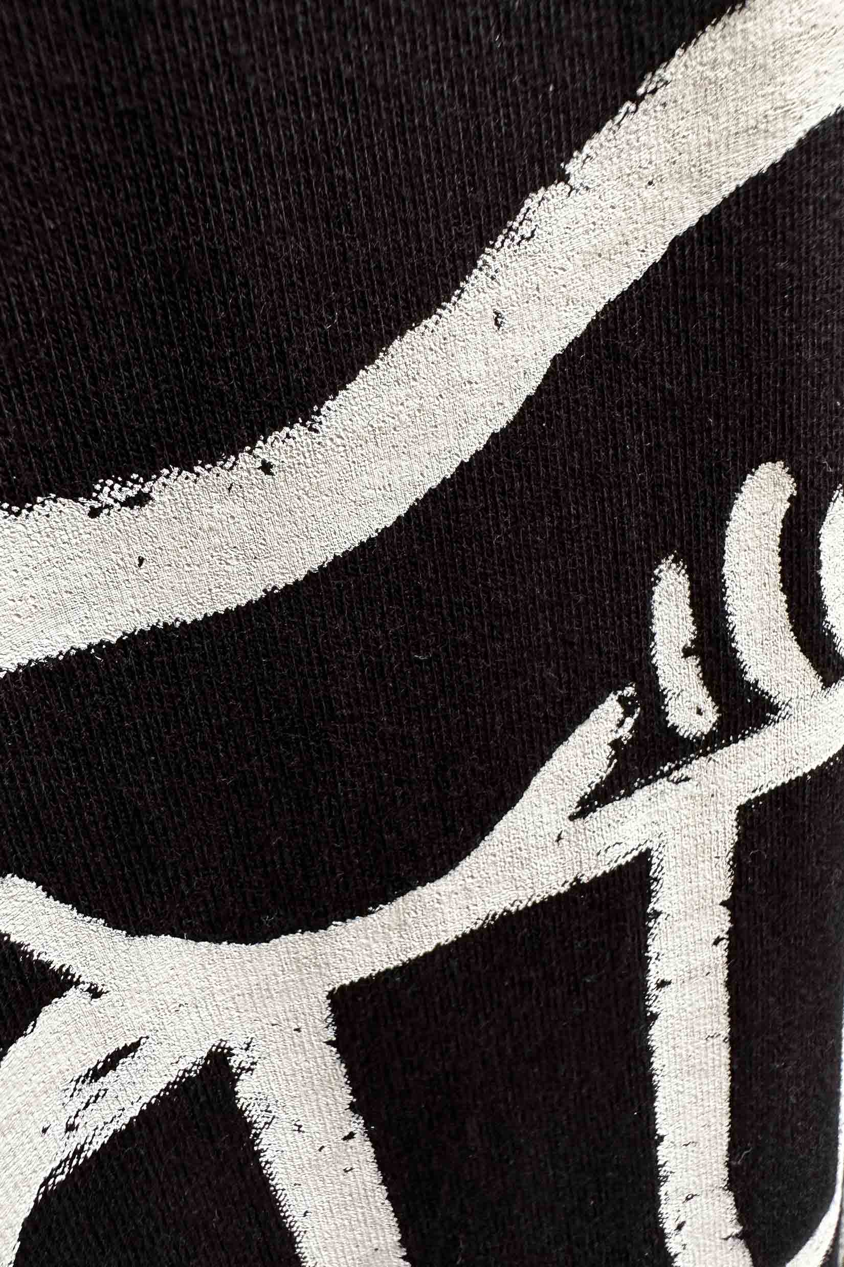 Stylera black T shirt close up showing white brushstroke abstract print on fabric trendy oversized art tee for men