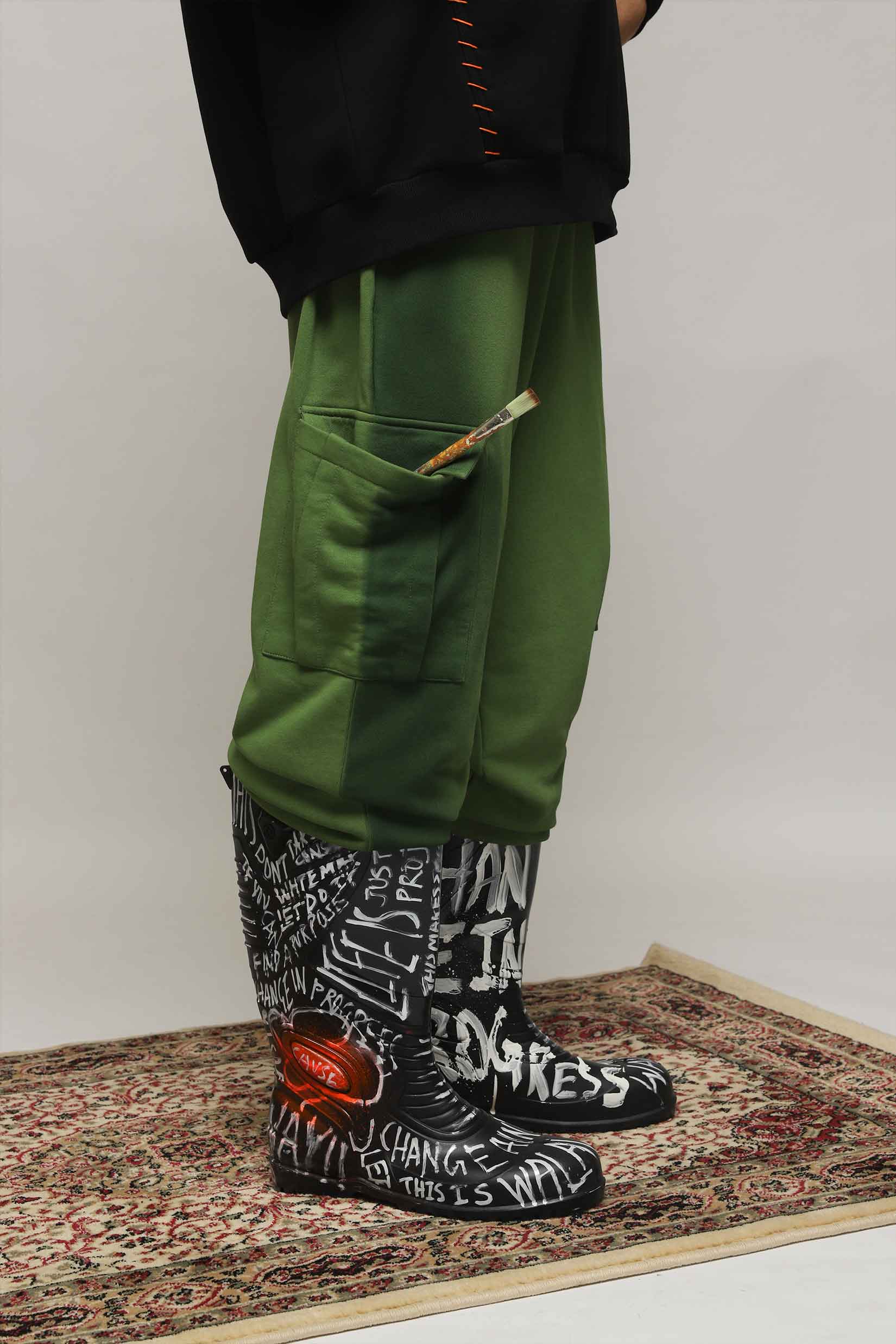 Stylera green cargo pocket joggers side view with pencil in pocket paired with graffiti boots on rug