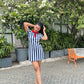 Model posing outdoors in a navy and white striped mini dress for women with red collar tie and red heels