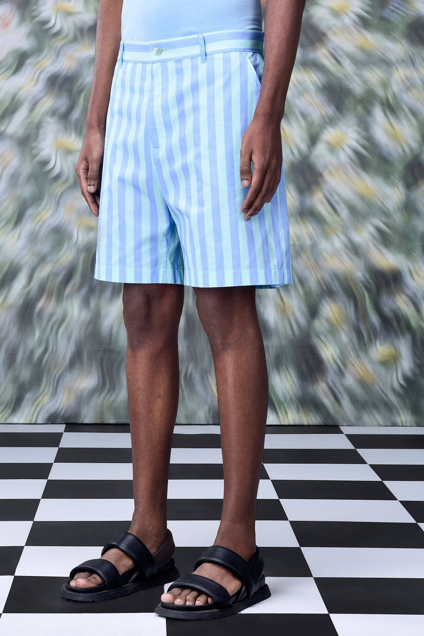 Stylera striped regular fit shorts in pastel blue and white vertical stripes on model with black sandals