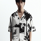 Stylera short sleeve button up black and white statement shirt with bold palm graphic print on model