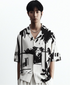 Stylera short sleeve button up black and white statement shirt with bold palm graphic print on model